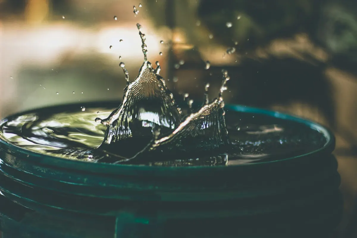 A drop of water splashing into a bucket under a leak